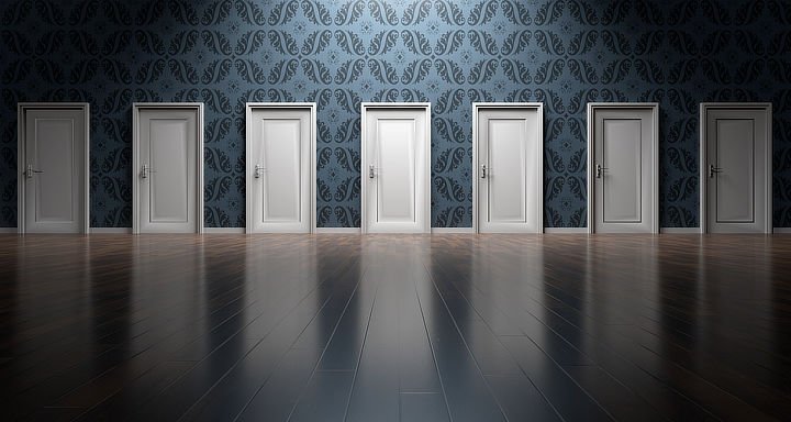 Series of white doors along a wall with a patterned wallpaper, signifying the choice that affiliate marketers need to make